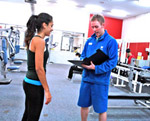 a male trainer with chart talking to atheletic woman.