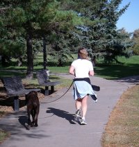 A person walking (jogging)  the dog.