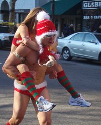 A couple in Santa Clause atire jogging down the street.