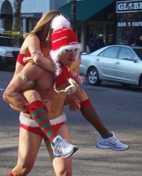 A couple in Santa Clause atire jogging down the street.